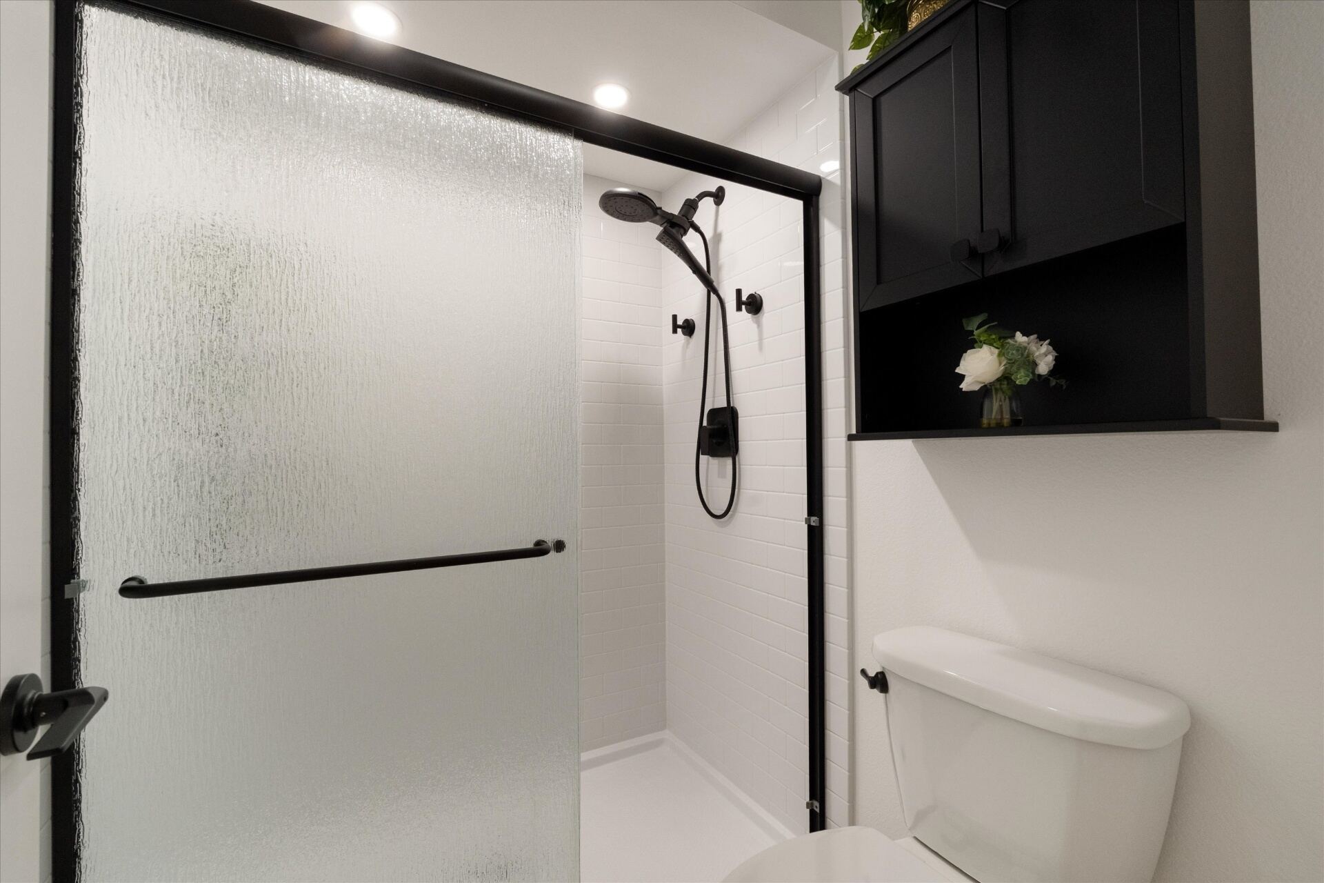 Primary bathroom walk-in shower with glass door and modern matte black fixtures