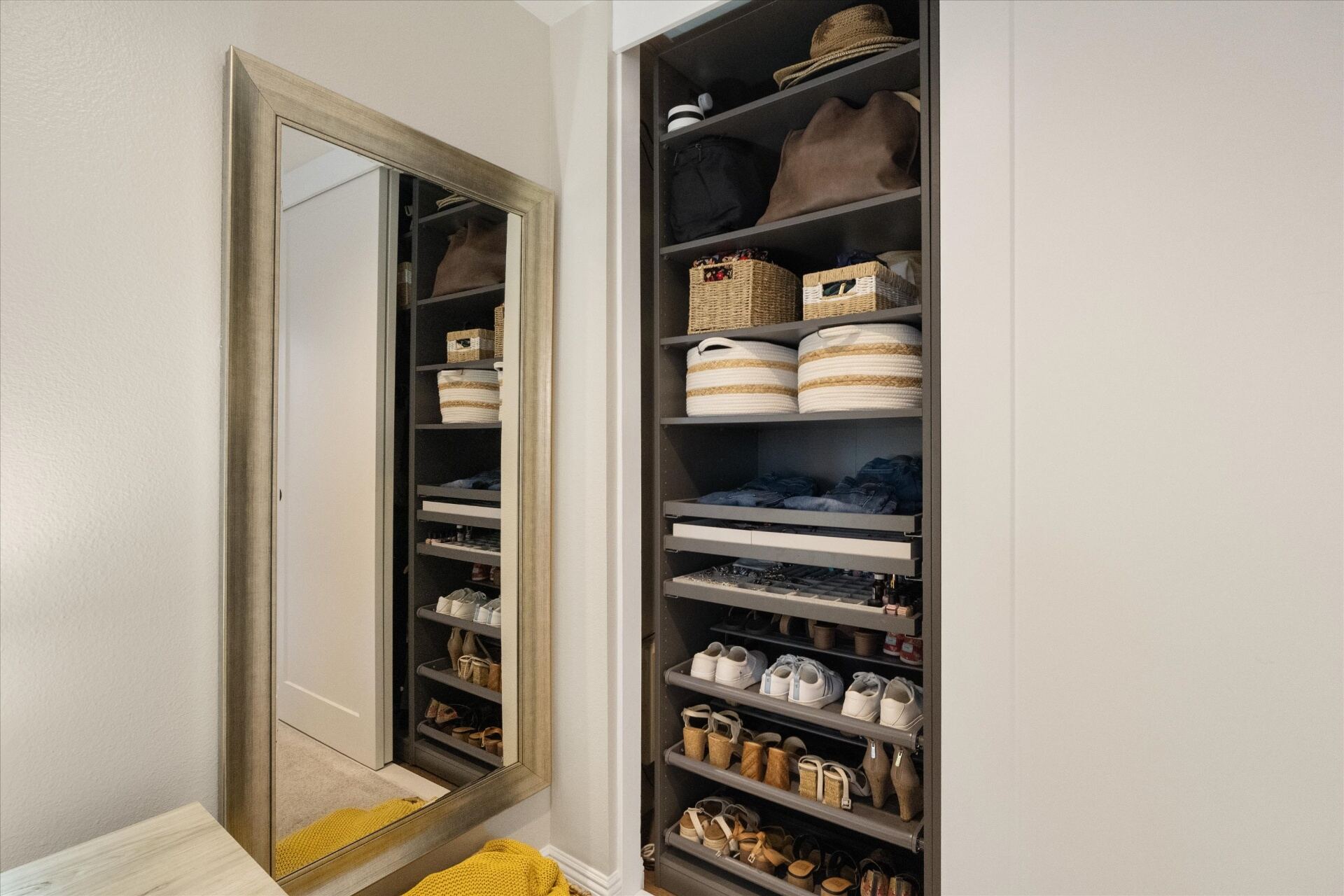 Primary bedroom walk-in closet with custom shelving and shoe storage